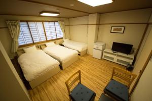 a small room with two beds and a television at City Kaigetsu in Sumoto