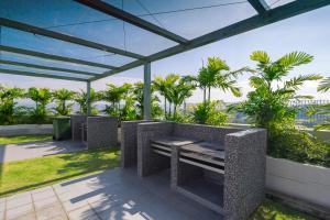 a patio with a bench and palm trees at Comfort Zone Premium Guesthouse @ Evo Bangi in Bangi