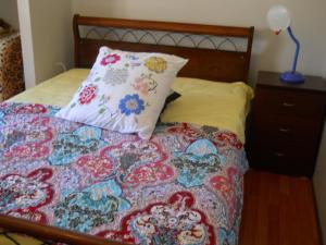 a bed with a colorful blanket and a pillow at Mimi's House in Perth