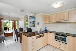 a kitchen with wooden cabinets and a dining room at Mantra Amphora in Palm Cove