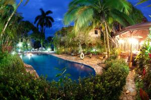 a swimming pool in a resort with palm trees at Hotel Villas Nicolas - Adults Only in Manuel Antonio