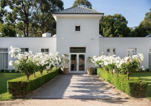 un bâtiment blanc avec des arbres à fleurs devant lui dans l'établissement Lancemore Lindenderry Red Hill, à Red Hill