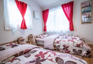 - 2 lits dans une chambre avec des rideaux rouges dans l'établissement Modern Machiya-Babacho, à Kyoto