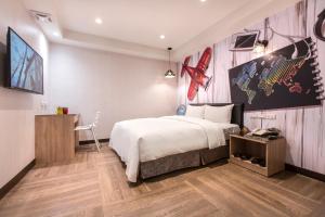 1 dormitorio con 1 cama, escritorio y TV en The Young Hotel, en Zhongli