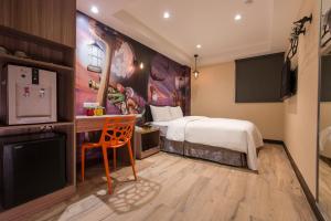 Schlafzimmer mit einem Bett, einem Schreibtisch und einem TV in der Unterkunft The Young Hotel in Zhongli