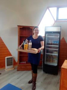 Eine Frau, die ein Tablett mit Essen in einem Kühlschrank hält. in der Unterkunft Chiloe Domos in Curaco de Velez
