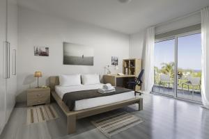 a white bedroom with a bed and a balcony at Myrtiana Villa in Protaras