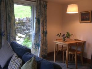 een woonkamer met een bank, een tafel en een raam bij Oban Seil Farm The Bothy in Clachan