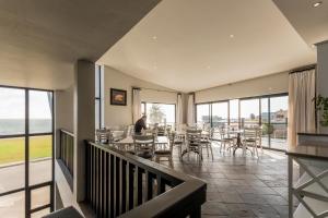 a dining room with tables and chairs and windows at Oyster Box Guesthouse in Walvis Bay