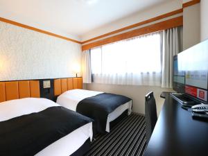 Habitación de hotel con 2 camas y escritorio con ordenador en APA Hotel Karuizawa Ekimae Karuizawaso en Karuizawa