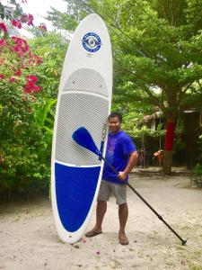 un hombre está sosteniendo una paleta y una tabla de surf en Alcove Bungalow, en Hinkong