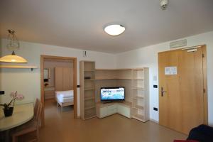 ein Wohnzimmer mit einem TV und ein Zimmer mit einem Tisch in der Unterkunft Hotel Stampfer B&B in Leifers