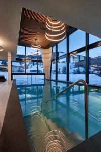 a large swimming pool in a building with windows at Hotel Störes - Living Nature Hotel in San Cassiano