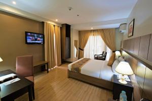 una camera d'albergo con letto e TV di The Pinnacle Hotel and Suites a Davao