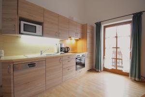 ガルミッシュ・パルテンキルヒェンにあるCarina, Martin, Michael & Sissiのキッチン(木製キャビネット付)、大きな窓が備わります。