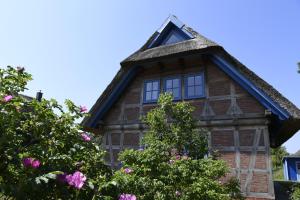 una casa vieja con techo de gambrel y flores rosas en Fachwerkhäuser Gager Haus „Strate“, en Gager