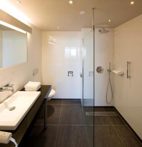 a bathroom with a glass shower and a sink at Van der Valk Hotel Stein Urmond in Urmond