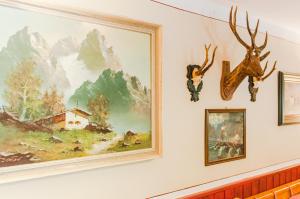 ein Gemälde an einer Wand mit Geweihen darauf in der Unterkunft Berggasthof Butzn Wirt in Ruhpolding
