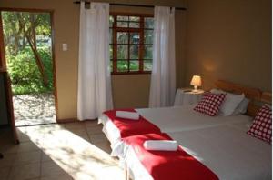 a bedroom with a large bed with a red and white blanket at Karoopark Guest House in Graaff-Reinet