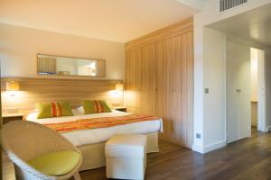 a bedroom with a bed and a chair and a mirror at Hôtel Vacances Bleues Delcloy in Saint-Jean-Cap-Ferrat