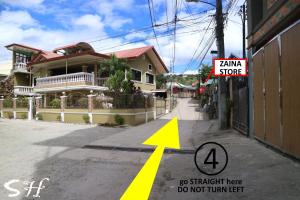 a street with a yellow arrow pointing to a house at Small House - Baguio in Baguio
