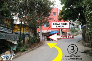 a city street with a sign that reads speed rolls bakery and turn left heretoo at Small House - Baguio in Baguio