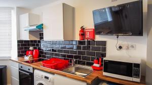 a kitchen with red kitchen utensils and a sink at UR City Pad - Richmond Apartments in Birmingham