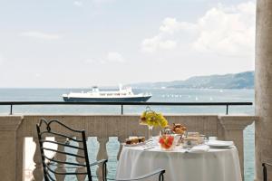 a table on a balcony with a cruise ship in the background at Savoia Excelsior Palace Trieste - Starhotels Collezione in Trieste