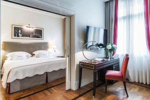 a hotel room with a bed and a desk and a chair at Savoia Excelsior Palace Trieste - Starhotels Collezione in Trieste