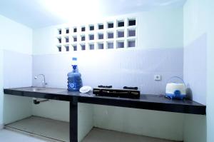 a kitchen counter with a sink and a bottle of water at RedDoorz near Museum Keraton Surakarta in Solo