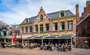 een groep mensen die aan tafels buiten een gebouw zitten bij Slapen bij hofman in Alkmaar