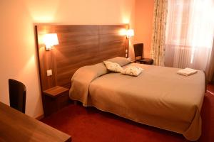 a hotel room with a bed with two pillows on it at Hôtel de Bourgogne in La Clayette