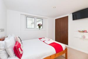 Schlafzimmer mit einem Bett mit roten und weißen Kissen in der Unterkunft Strawberry Fields in Brighton & Hove