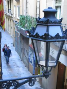 een straatlantaarn met een stel dat over straat loopt bij PENSIÓN Colmenero in Barcelona