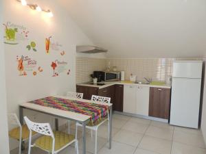 una cucina con tavolo, sedie e frigorifero di Apartments SVI-MI a Gradac (Grado)