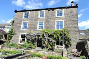 a brick house with flowers in front of it at Burnlee House Apartment in Holmfirth