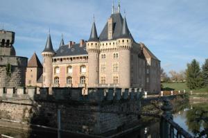 a castle on the side of a river at Hôtel de Bourgogne in La Clayette