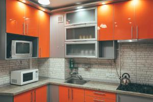 a kitchen with orange cabinets and a sink and a microwave at Prime Home in Chernihiv