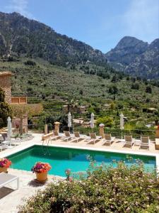 una piscina con sillas y montañas en el fondo en Hotel Apartament Sa Tanqueta De Fornalutx - Adults Only en Fornalutx