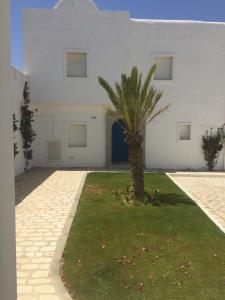a palm tree in front of a white building at Villa avec piscine in Triffa