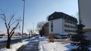 a white building with a black roof in the snow at Apartmani Ana in Slatina