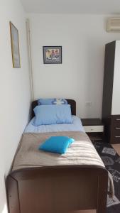 a bed with a blue pillow on top of it at Apartmani Ana in Slatina