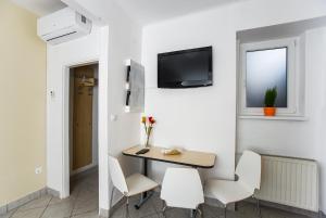 Habitación con mesa, sillas y TV en la pared. en Roze Apartment, en Zagreb
