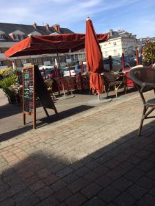 patio ze stołami, krzesłami i parasolem w obiekcie Hôtel de la poste w mieście Saint-Valéry-en-Caux