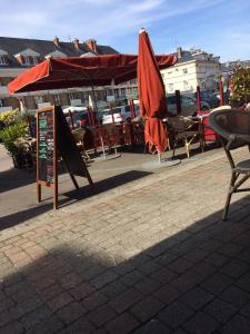 a patio with tables and chairs and an umbrella at Hôtel de la poste in Saint-Valery-en-Caux