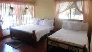 two beds sitting in a room with windows at Bright Star Hotel in Arusha