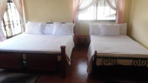 two beds in a room with two windows at Bright Star Hotel in Arusha