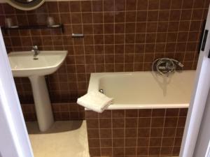 a bathroom with a bath tub and a sink at Hôtel de la poste in Saint-Valery-en-Caux