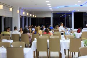 a group of people sitting at tables in a restaurant at AGZ Hotel in Dikili
