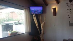 TV en la pared en una habitación con ventana en Chalets, Cabañas Terramaría de Potrerillos en Potrerillos